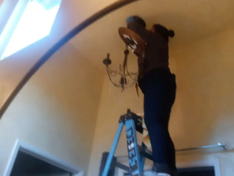 Electrician installing a chandelier in a Eunice residence